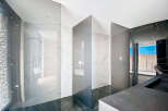 Luxury bathroom with marble walls and glass partitions.