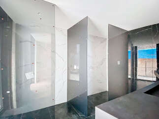 Luxury bathroom with marble walls and glass partitions.