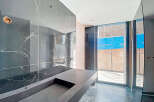 This stunning bathroom boasts a sleek, modern design with dark marble walls and a custom concrete sink.