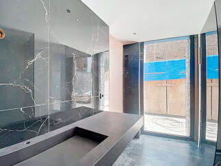 This stunning bathroom boasts a sleek, modern design with dark marble walls and a custom concrete sink.