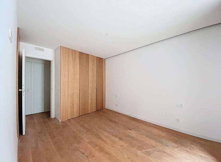 This stunning bedroom boasts a minimalist design with light wood flooring and built-in wooden closet.