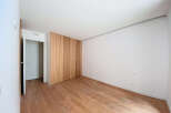 This stunning bedroom boasts a minimalist design with light wood flooring and built-in wooden closet.