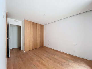 This stunning bedroom boasts a minimalist design with light wood flooring and built-in wooden closet.