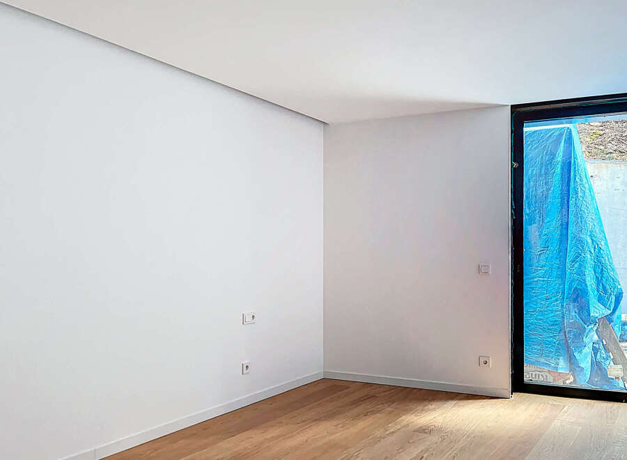 This stunning property boasts a spacious, bright room with sleek white walls and elegant light oak hardwood flooring.