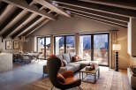 This stunning penthouse boasts a spacious open-plan living area with vaulted ceilings and exposed wooden beams, creating a warm and inviting atmosphere.