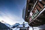 Nestled in a breathtaking snowy mountain setting, this charming pizzeria boasts a rustic wooden exterior with a unique overhanging design.