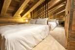 Cozy chalet bedroom with rustic wood beams and plush bedding.