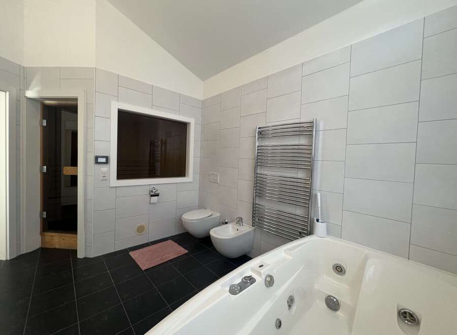 This luxurious bathroom features a modern design with sleek, light-colored tiles and a spacious layout.