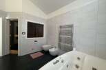 This luxurious bathroom features a modern design with sleek, light-colored tiles and a spacious layout.