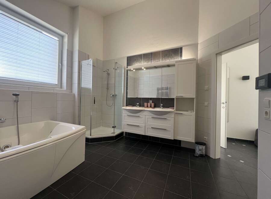 This modern bathroom features a sleek design with a luxurious bathtub and a separate shower.