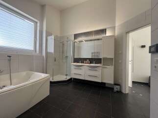 This modern bathroom features a sleek design with a luxurious bathtub and a separate shower.
