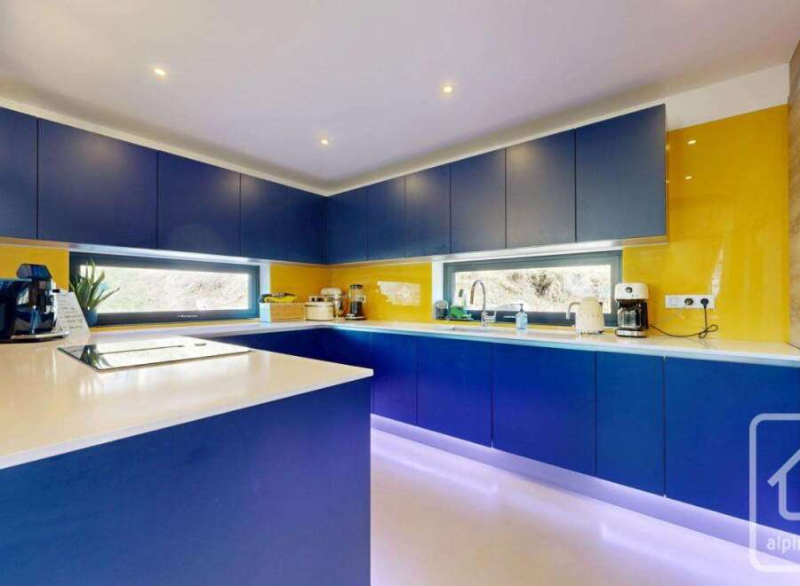 This modern kitchen boasts a sleek design with vibrant blue cabinetry and a contrasting white countertop.