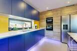 This modern kitchen boasts sleek, blue cabinetry and a bright yellow backsplash, creating a vibrant and stylish space.