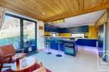 This stunning property boasts a modern kitchen with sleek blue cabinetry and a vibrant yellow backsplash, perfect for culinary enthusiasts.