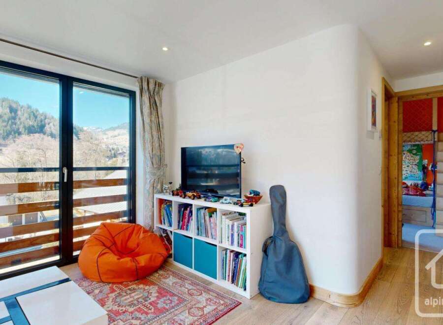 Discover this charming property featuring a cozy living space with a vibrant orange beanbag and a stylish bookshelf.