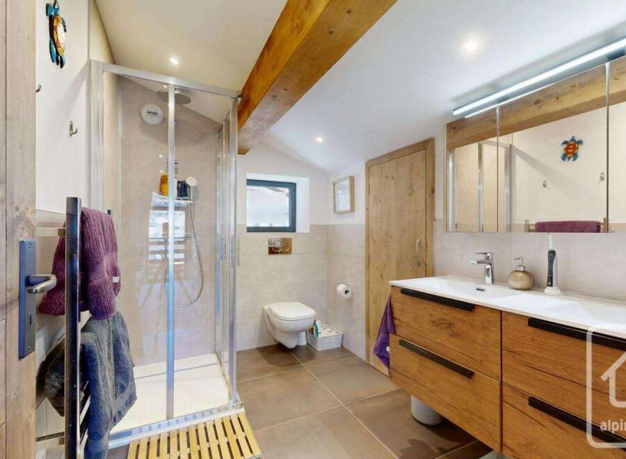 Discover the charm of this beautifully designed bathroom, featuring a modern glass shower and stylish wooden accents.
