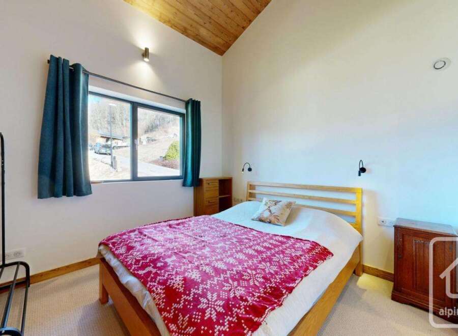This cozy bedroom features a comfortable bed with a vibrant red patterned blanket, perfect for a relaxing retreat.
