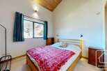 This cozy bedroom features a comfortable bed with a vibrant red patterned blanket, perfect for a relaxing retreat.