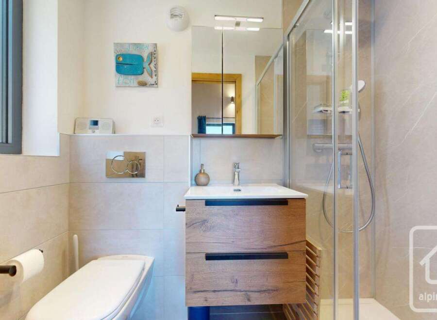 This modern bathroom features a sleek design with a wooden vanity and a glass shower enclosure.