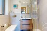 This modern bathroom features a sleek design with a wooden vanity and a glass shower enclosure.