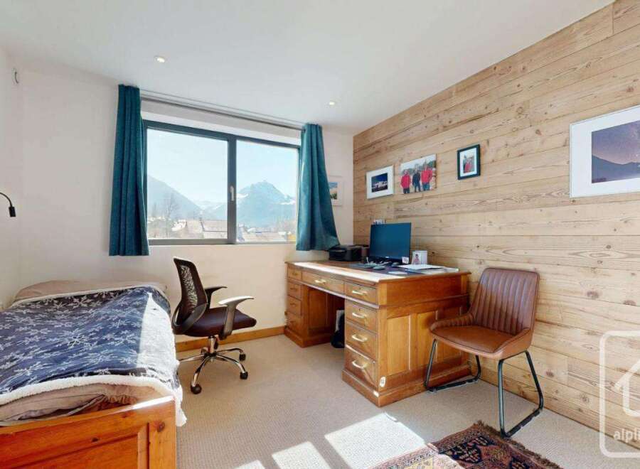Discover this charming bedroom featuring a cozy bed, a functional desk, and a stunning view.