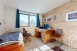 Discover this charming bedroom featuring a cozy bed, a functional desk, and a stunning view.