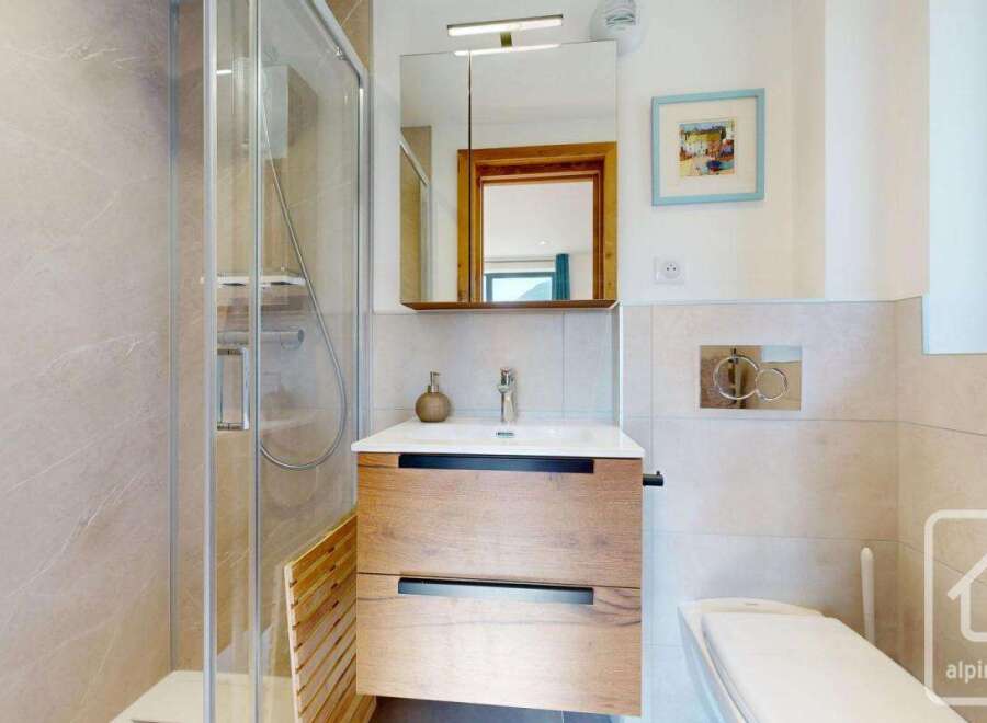Discover this modern bathroom featuring a sleek glass shower and a stylish wooden vanity.