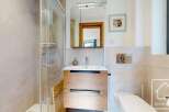 Discover this modern bathroom featuring a sleek glass shower and a stylish wooden vanity.