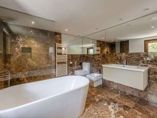 Luxurious bathroom with marble flooring and walls, featuring a freestanding bathtub, walk-in shower, and modern vanity.