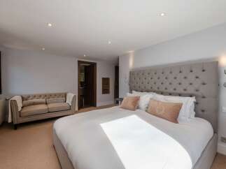 Luxurious bedroom with a king-size bed, plush bedding, and a tufted headboard.