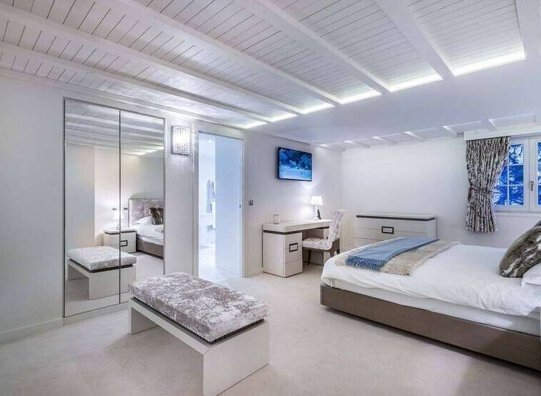 Luxurious bedroom with built-in wardrobe and bench seating.