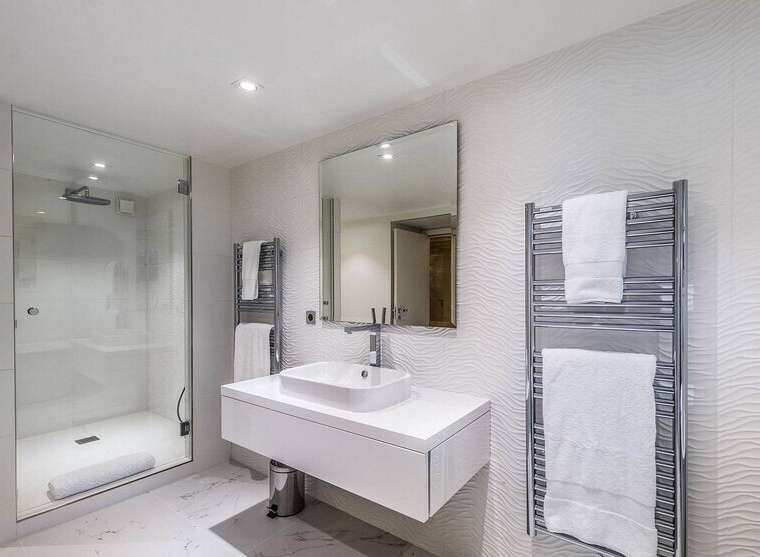 Modern bathroom with a walk-in shower, heated towel rack, and floating vanity.