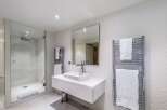 Modern bathroom with a walk-in shower, heated towel rack, and floating vanity.