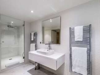 Modern bathroom with a walk-in shower, heated towel rack, and floating vanity.