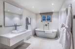 Luxurious bathroom with a freestanding bathtub, modern sink, and heated towel rack.