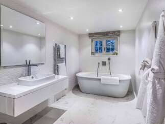 Luxurious bathroom with a freestanding bathtub, modern sink, and heated towel rack.