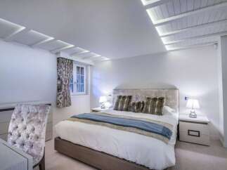 Luxurious bedroom with a plush velvet headboard and soft bedding.