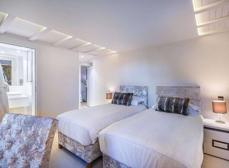 Luxurious twin bedroom with plush velvet headboards and crisp white linens.