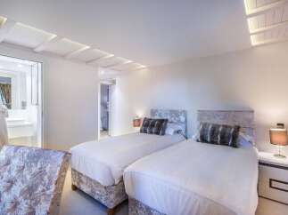 Luxurious twin bedroom with plush velvet headboards and crisp white linens.