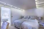 Luxurious twin bedroom with plush velvet headboards and soft grey bedding.