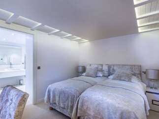 Luxurious twin bedroom with plush velvet headboards and soft grey bedding.