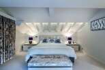 Luxurious chalet bedroom with stunning sloped ceilings and plush velvet furnishings.
