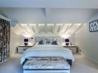 Luxurious chalet bedroom with stunning sloped ceilings and plush velvet furnishings.