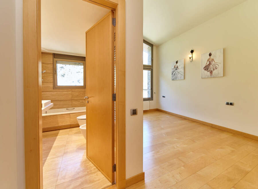 This stunning property boasts a spacious bedroom with light hardwood floors and two elegant ballerina-themed wall art pieces.