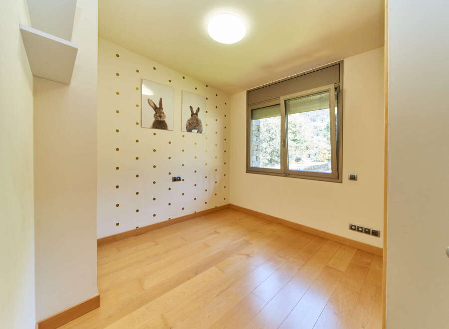 Light and airy bedroom with wood flooring and large window.