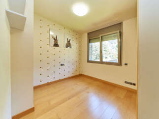 Light and airy bedroom with wood flooring and large window.