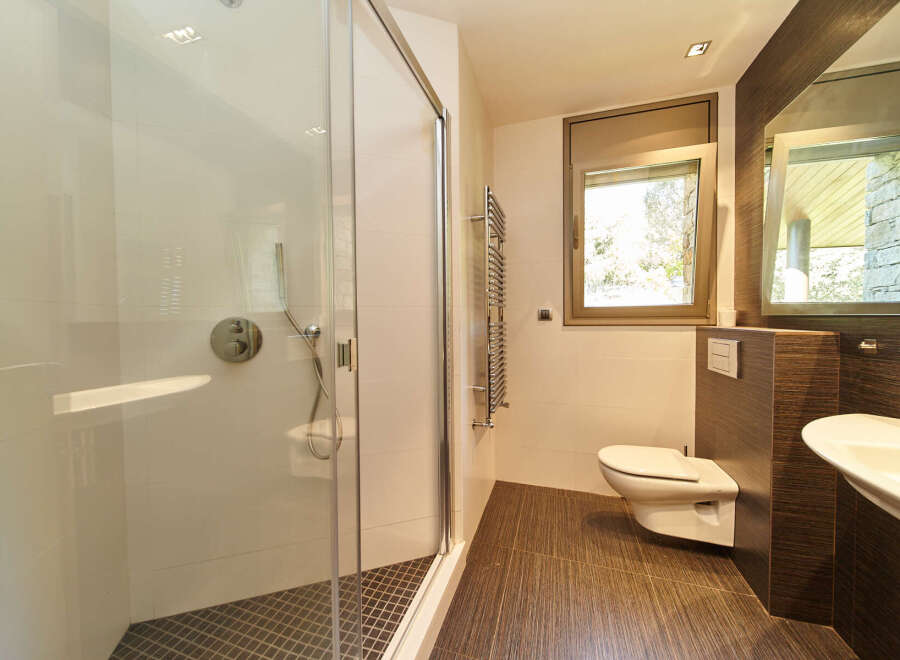 This stunning bathroom boasts a spacious shower enclosure with modern fixtures, complemented by a sleek, wall-mounted toilet.
