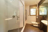This stunning bathroom boasts a spacious shower enclosure with modern fixtures, complemented by a sleek, wall-mounted toilet.