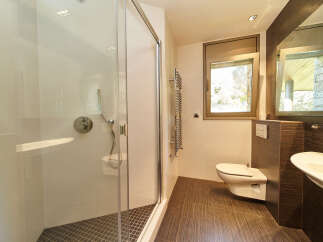 This stunning bathroom boasts a spacious shower enclosure with modern fixtures, complemented by a sleek, wall-mounted toilet.