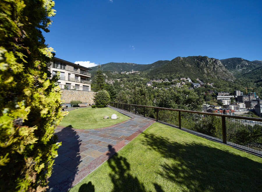 This stunning property boasts a beautifully landscaped garden with a paved pathway, offering breathtaking views of the surrounding mountains.